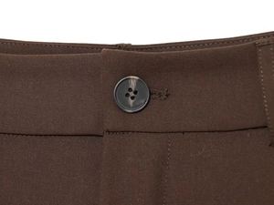 Close-up of houndstooth pants waist featuring a dark grey round button and woven fabric