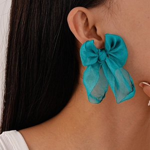Close-up of elegant turquoise organza bow earring worn by a model in a profile view