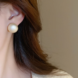 Close-up of a model wearing a matte champagne gold geometric pearl stud earring