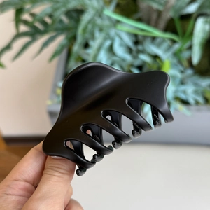 Détail rapproché de la pince à cheveux noire mate montrant sa charnière à ressort robuste