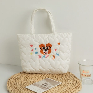 Detail of white quilted lunch bag featuring heart patterns and cute puppy embroidery