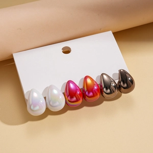 Detail view of 3 pairs of teardrop earrings with metallic pearl, pink and grey finishes