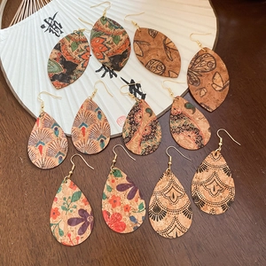 Detailed flat lay of ethnic faux leather teardrop earrings with floral and butterfly prints