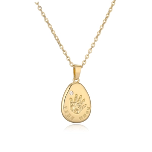 Collana con ciondolo a goccia dorata con impronta di mano e piccolo diamante su bianco