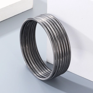 Stackable 3mm minimalist black titanium steel round bangles on a textured stone display