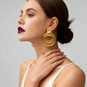 Polished gold geometric multilayer hoop earrings worn by a model in a side profile shot