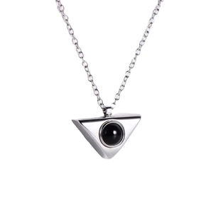 Macro detail of a silver geometric triangle pendant necklace with a black stone inlay