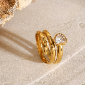 Macro detail of a gold spiral heart ring featuring a clear heart-shaped cubic zirconia stone