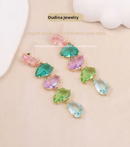 Detailed view of colorful drop earrings with multi-colored stones on gold base