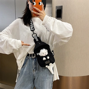 Detail of black canvas crossbody bag featuring a cute white lamb plush and wide strap
