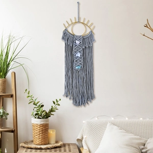 Detail of grey macrame wall hanging with evil eye design and blue raw stones