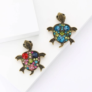 Vintage alloy turtle brooches with colorful rhinestones on a white geometric stand