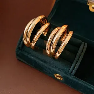 Boucles d'oreilles créoles dorées multicouches en forme de C sur boîte en velours bleu
