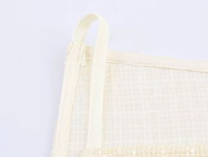 Détail macro du gant exfoliant beige avec boucle de suspension et bordure cousue