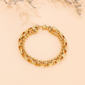 Detailed shot of double-layered gold chain bracelet featuring bead and box link textures