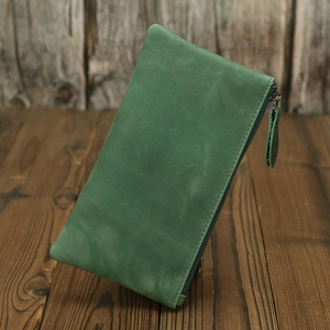 Detail of green crazy horse leather wallet with zipper on a dark wooden surface