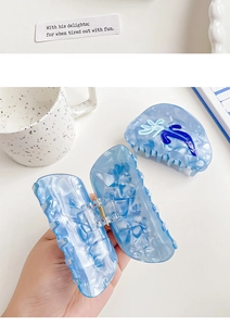 Macro detail of a light blue marble acetate hair claw with floral and bow accents