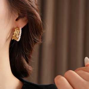 Detail of vintage gold pearl earrings with lace texture and zircon worn by a model