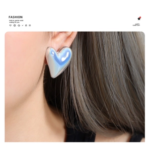 Close-up of a model wearing holographic heart stud earrings in polished gold finish