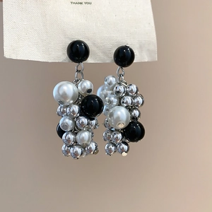 Macro detail of clustered pearl and bead tassels earrings on a display card