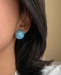 Gros plan de boucles d'oreilles rondes en résine marbrée bleue portées par un mannequin