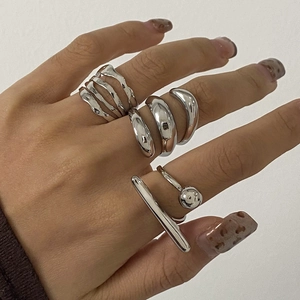 Silver geometric stainless steel rings stacked on fingers with minimalist wavy and round designs