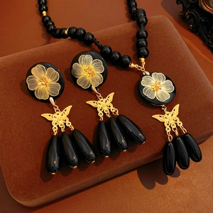 Macro detail of vintage necklace and earring set with golden flowers and black beads