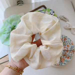 Close-up of beige polka dot scrunchie with soft cotton-linen texture and floral hair ties