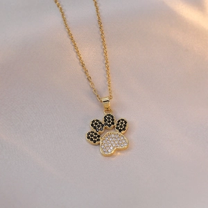 Golden paw print pendant necklace with black and white zircon on silk background