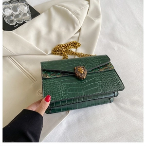 Detail of dark green croc-effect shoulder bag with gold lion buckle and metal chain