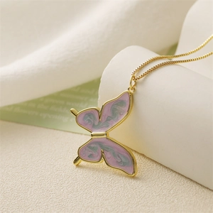 Close-up of golden butterfly pendant with pink and green enamel wings on a fine chain