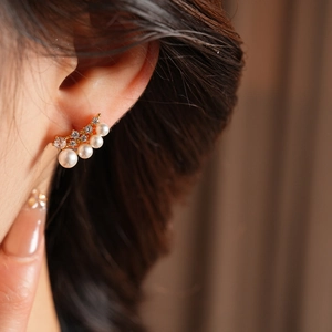 Close-up of elegant 18k gold plated curved earring with white pearls and zircons