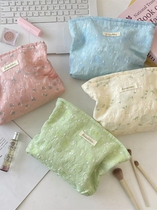 Quilted floral jacquard cosmetic bags in pastel pink, blue, cream, and green colors