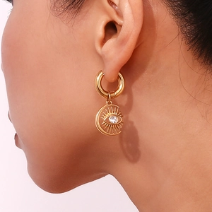 Close-up of gold moon and eye drop earring with sparkling zircon on a female model