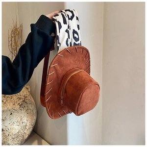 Close-up of brown suede cowboy hat bag with stylish cow print strap and zipper detail