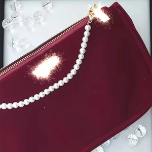 Elegant burgundy velvet cosmetic bag featuring a premium white pearl zipper chain strap