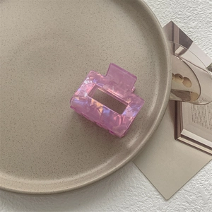 Dettaglio di un fermaglio rettangolare in acetato viola iridescente con finitura perlata