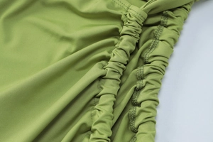 Close-up detail of avocado green knitted fabric with elegant ruched texture and stitching