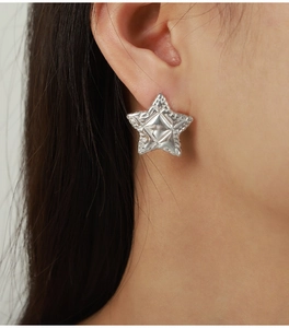 Détail de boucles d'oreilles étoiles argentées avec texture 3D sur l'oreille