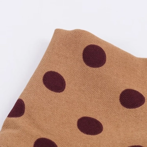 Detail of tan fabric with deep red polka dots showing woven texture and high quality finish