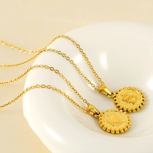 Detailed close-up of 18k gold-plated coin pendants with letter B and heart sunburst engraving