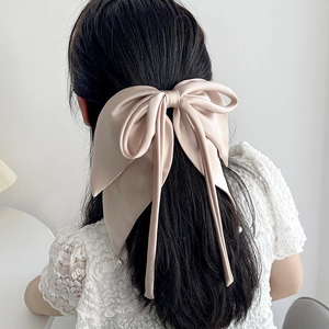 Champagne satin ribbon bow hair clip worn on long hair for a stylish hair accessory