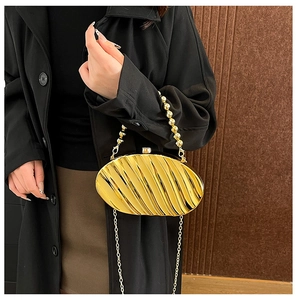 Detail of leaf-shaped acrylic evening clutch with gold pleat texture and bead handle