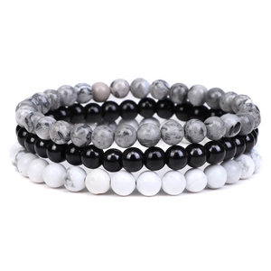 Macro detail of three-piece beaded bracelet set featuring black, white, and grey natural stones