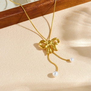Gold plated bow necklace with white pearl pendants on elegant beige snake chain