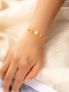Detailed view of an 18k gold plated bracelet featuring emerald flower and heart charms