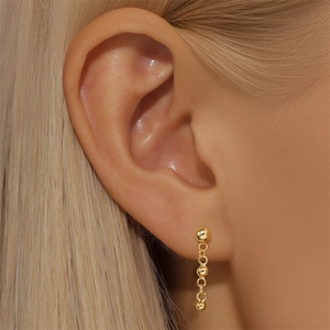 Detailed close-up of golden S925 silver earring with triple ball drop chain on ear