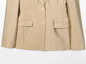 Detail van champagnegouden blazer met zijdeachtige textuur en knoopsluiting
