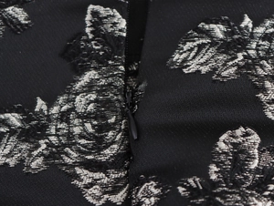 Detail of silver floral jacquard fabric with a black invisible zipper and sleek metal pull