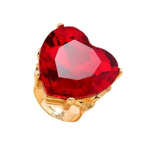 Deep red heart-shaped gemstone ring with gold-plated band in a minimalist display